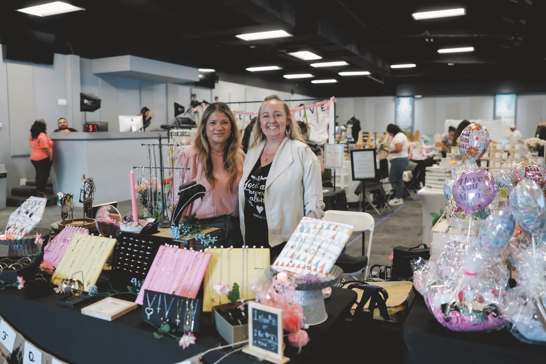 Two smiling vendors at their jewelry booth at the A Company of Women OC Spring Market